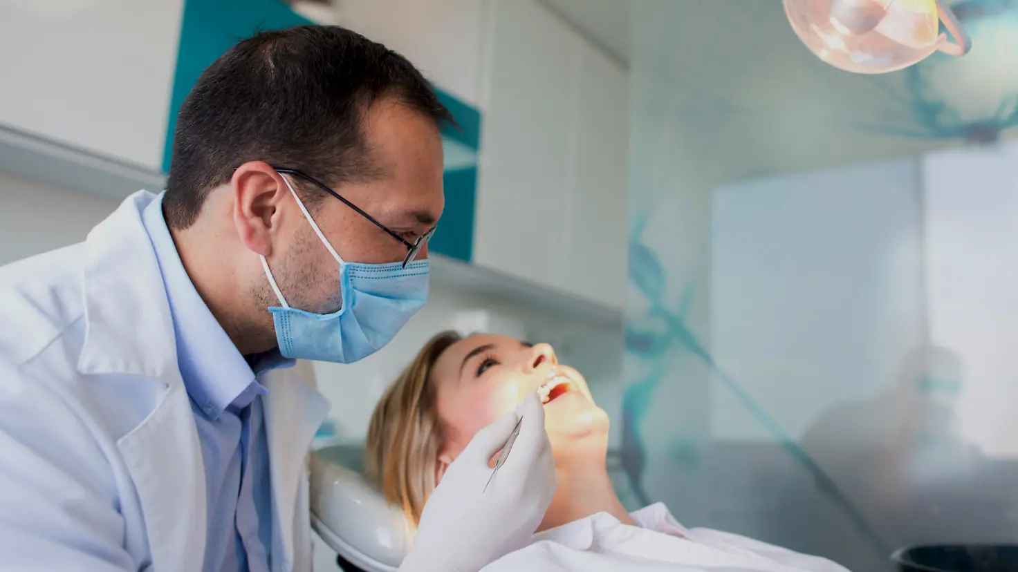 Eine Frau wird von einem Zahnarzt auf Karies untersucht.