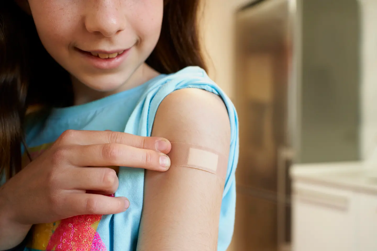 Oberarm eines Mädchens mit hautfarbenem Heftpflaster
