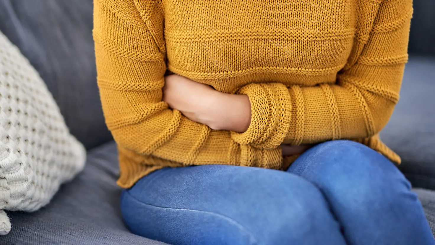 Frau hält sich ihren schmerzenden Bauch.