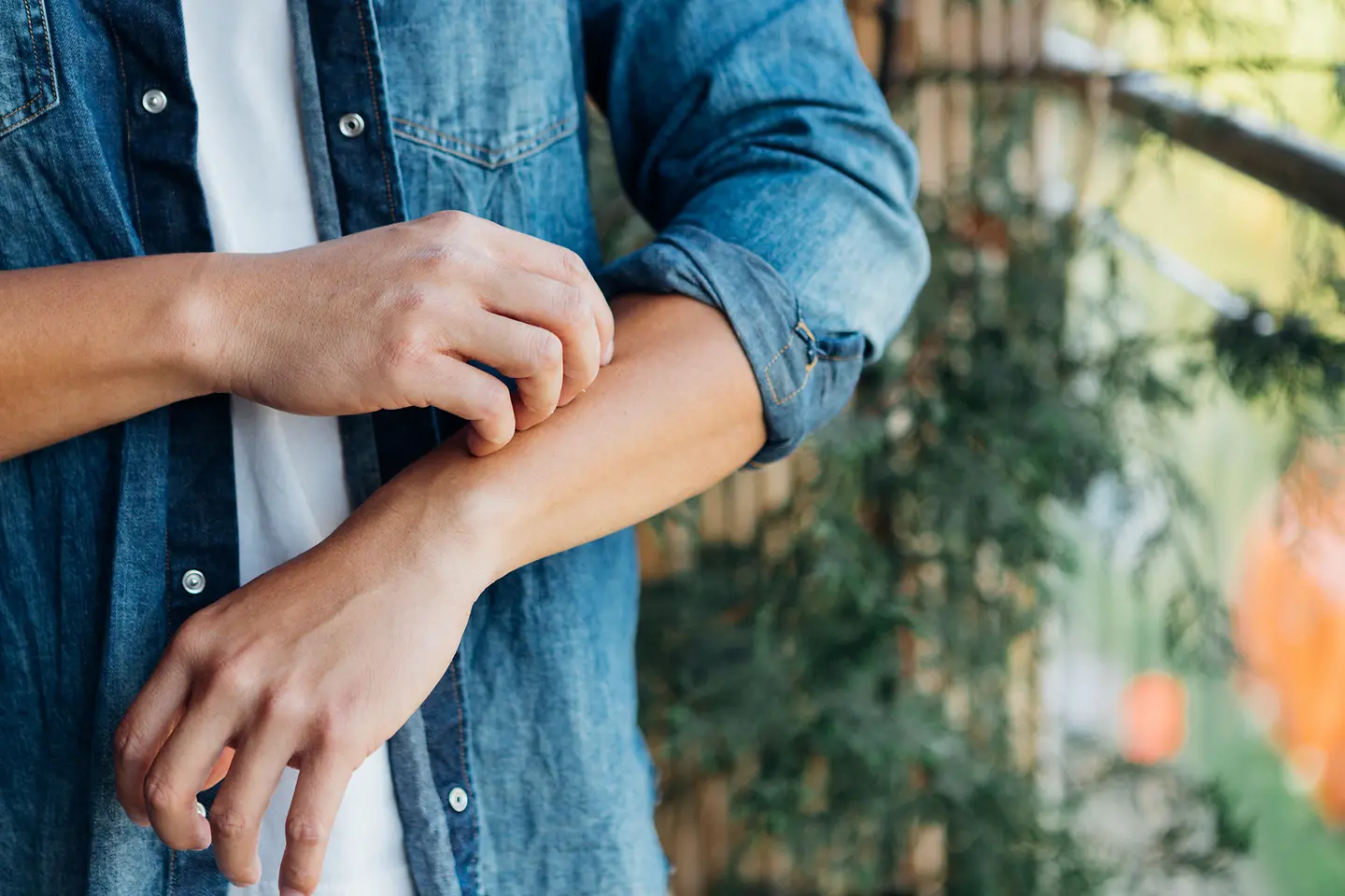 Ein Mann kratzt sich den Unterarm