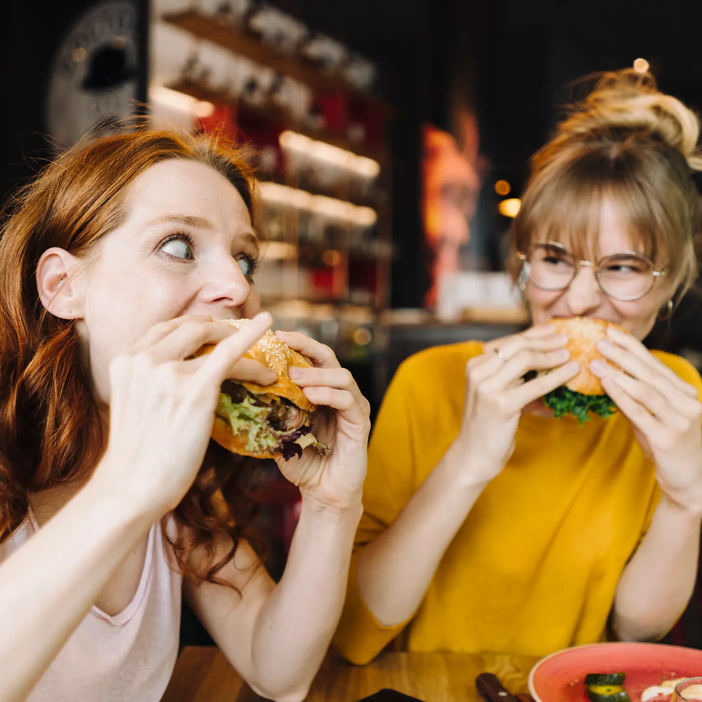 Zwei junge Frau sitzen in einem Restaurant und essen Burger