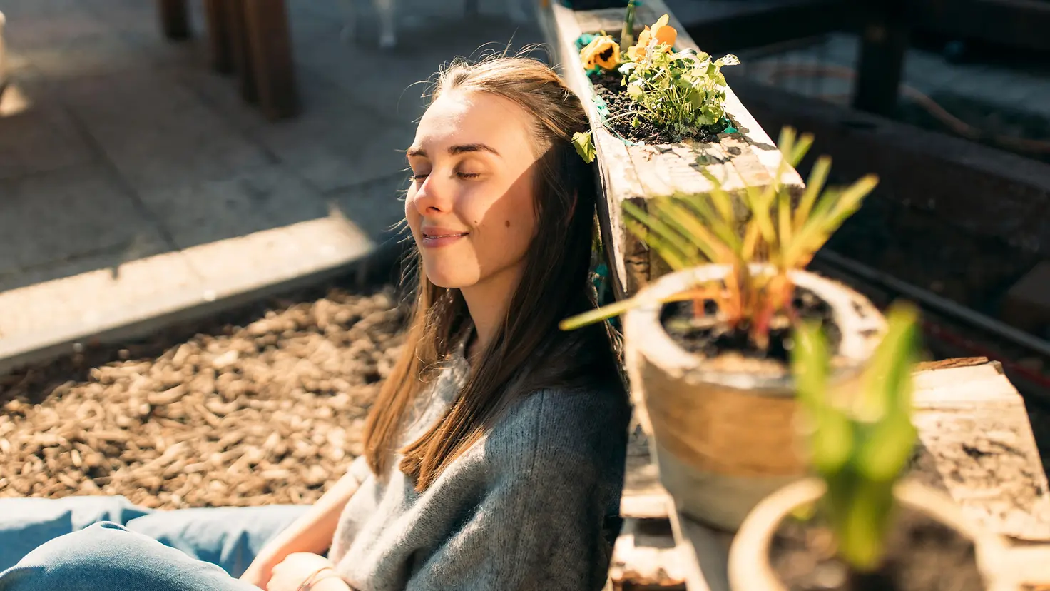 Eine junge Frau genießt die Sonne in einem Garten