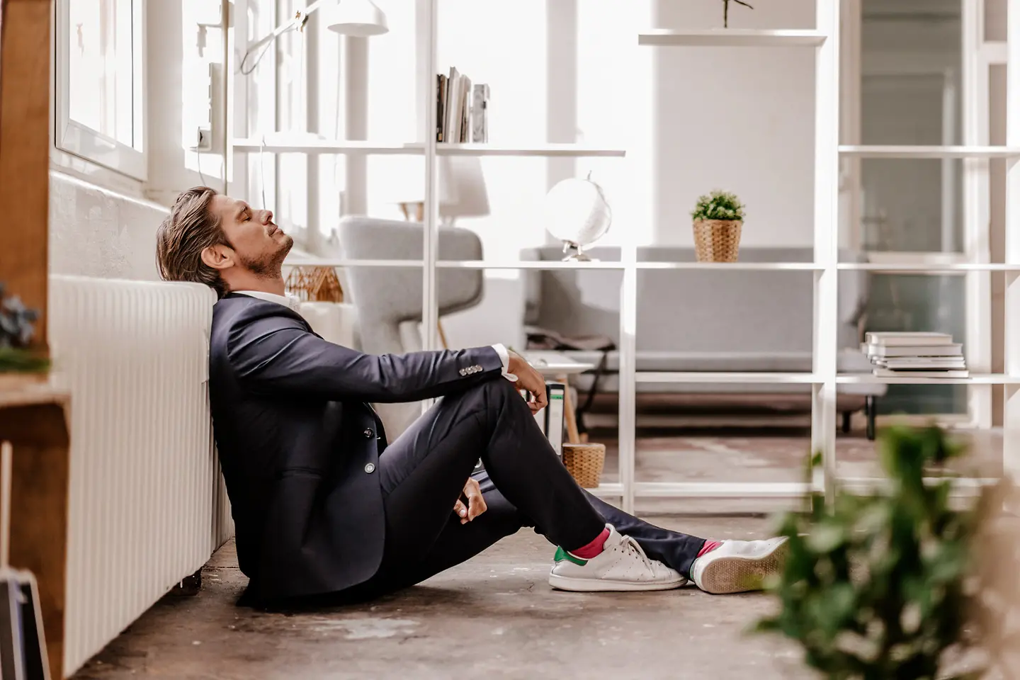 Mann im Anzug sitzt auf dem Fußboden seines Büros