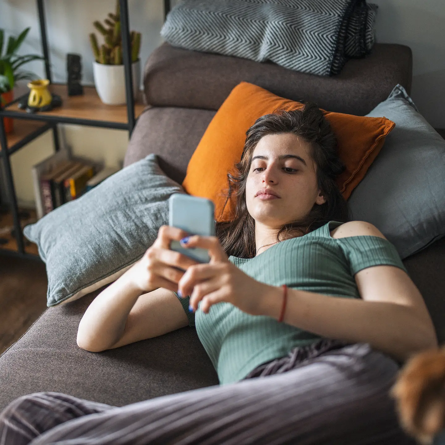 Eine junge Frau auf dem Sofa mit einem Smartphone