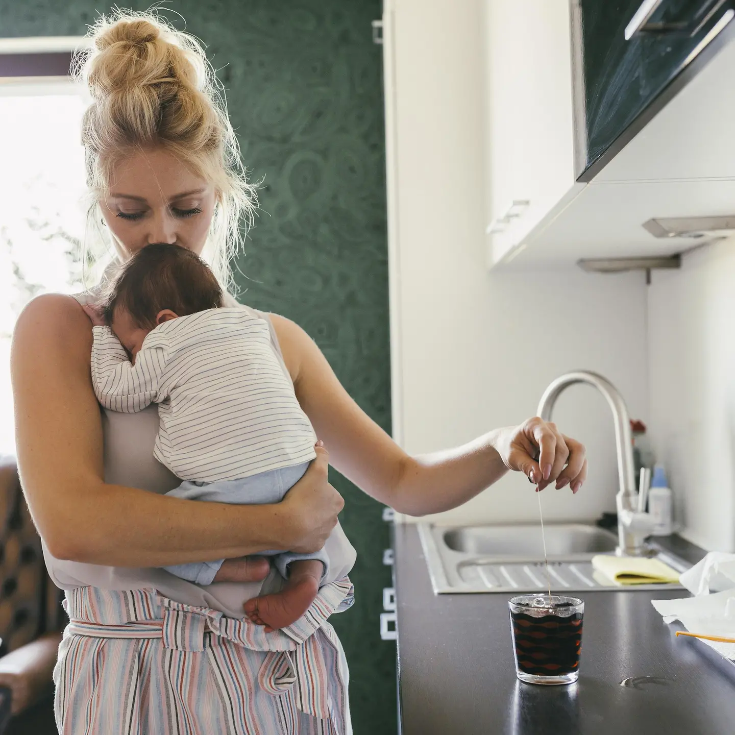 Mutter hält ihr Baby auf dem Arm während Sie in der Küche steht