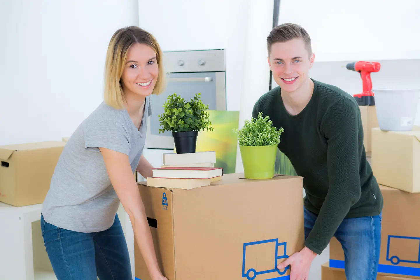 Zu sehen ist sind Mutter und Sohn beim tragen eines Umzugskartons