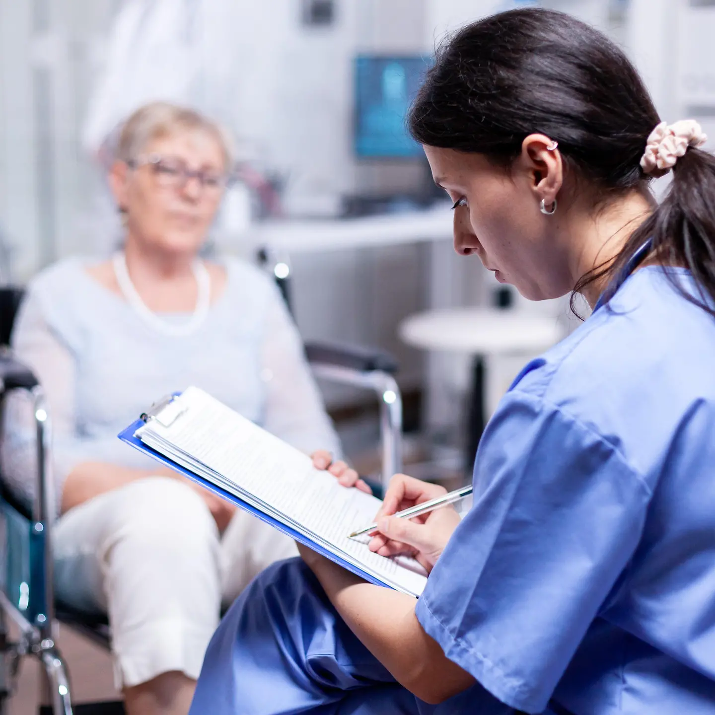 Eine Pflegeperson notiert etwas auf einem Klemmbrett