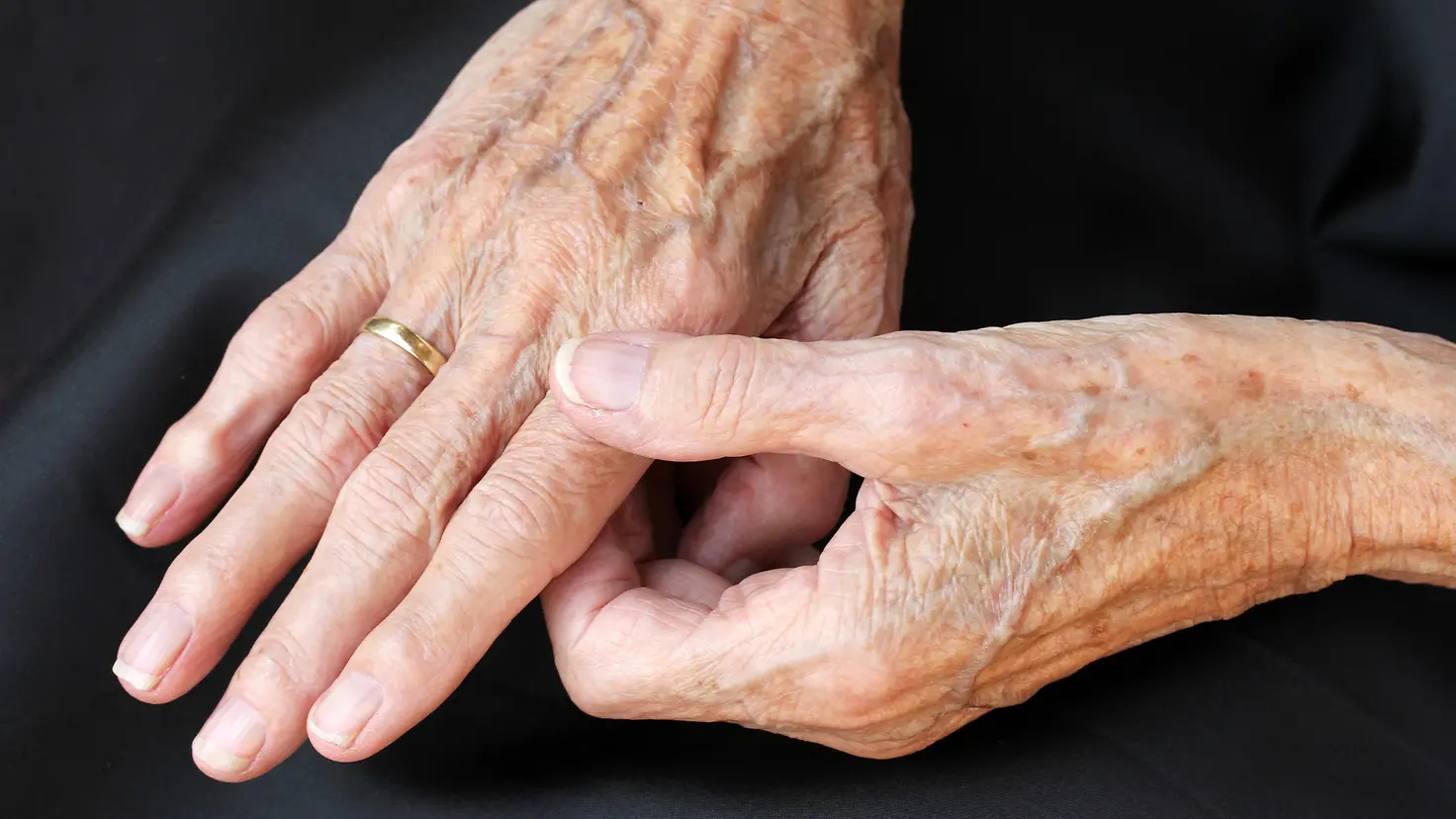 Zu sehen auf diesem Bild sind ein Paar Hände eines älteren Menschen. Der Zeigefinger der rechten Hand wird dabei durch einen Griff mit Daumen-Zeigefinger der linken Hand gehalten.