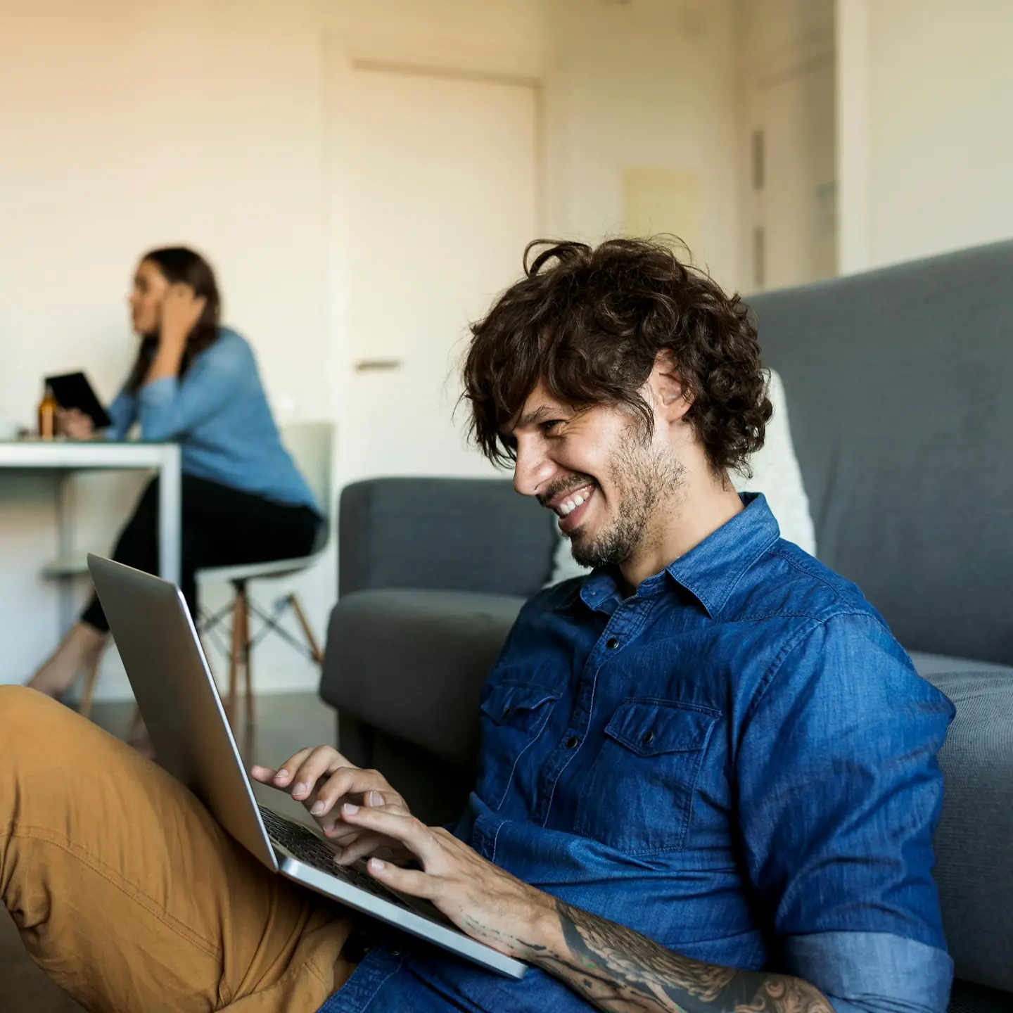 Ein junger Mann mit Laptop sitzt auf dem Boden einer WG