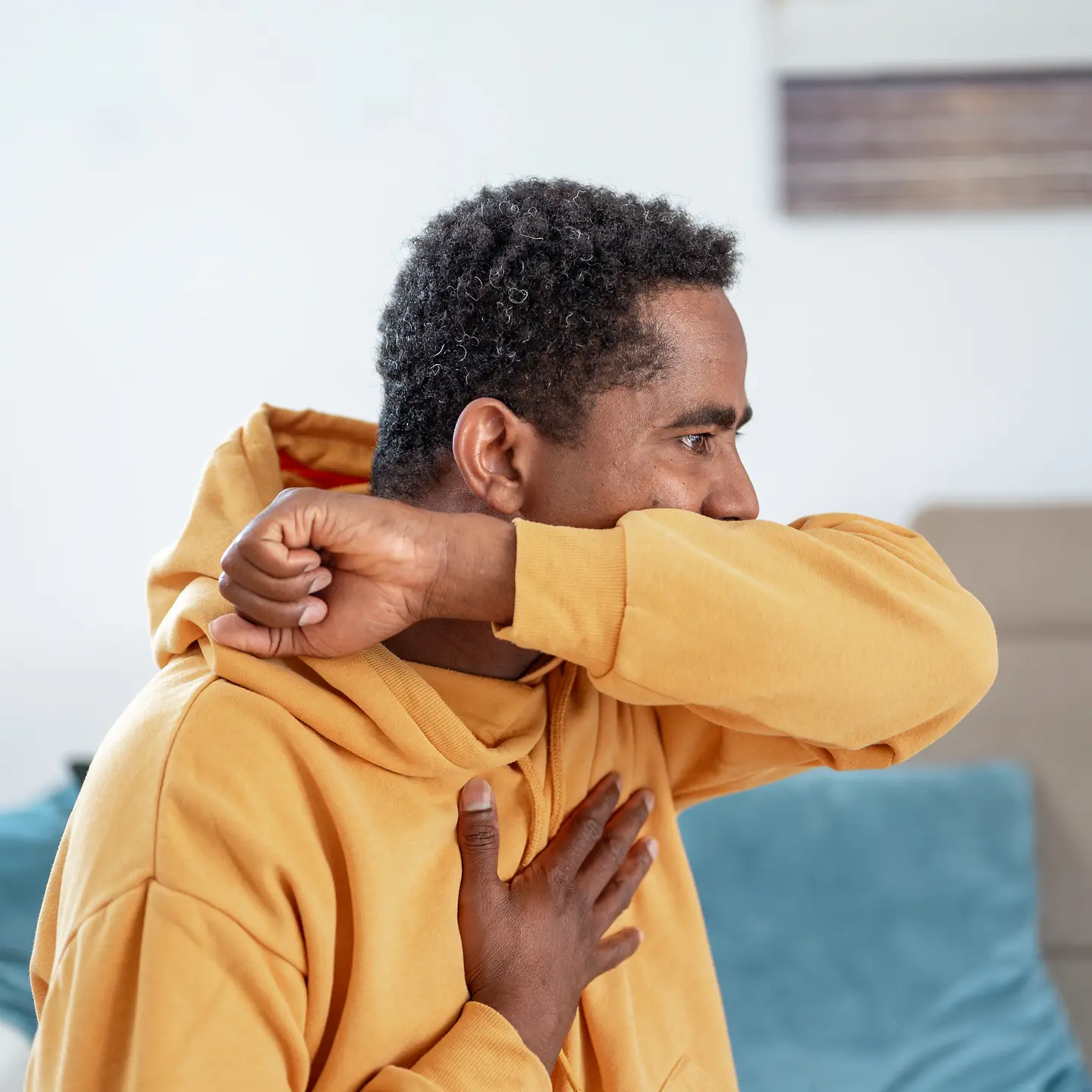 Ein Mann hustet in seine Armbeuge