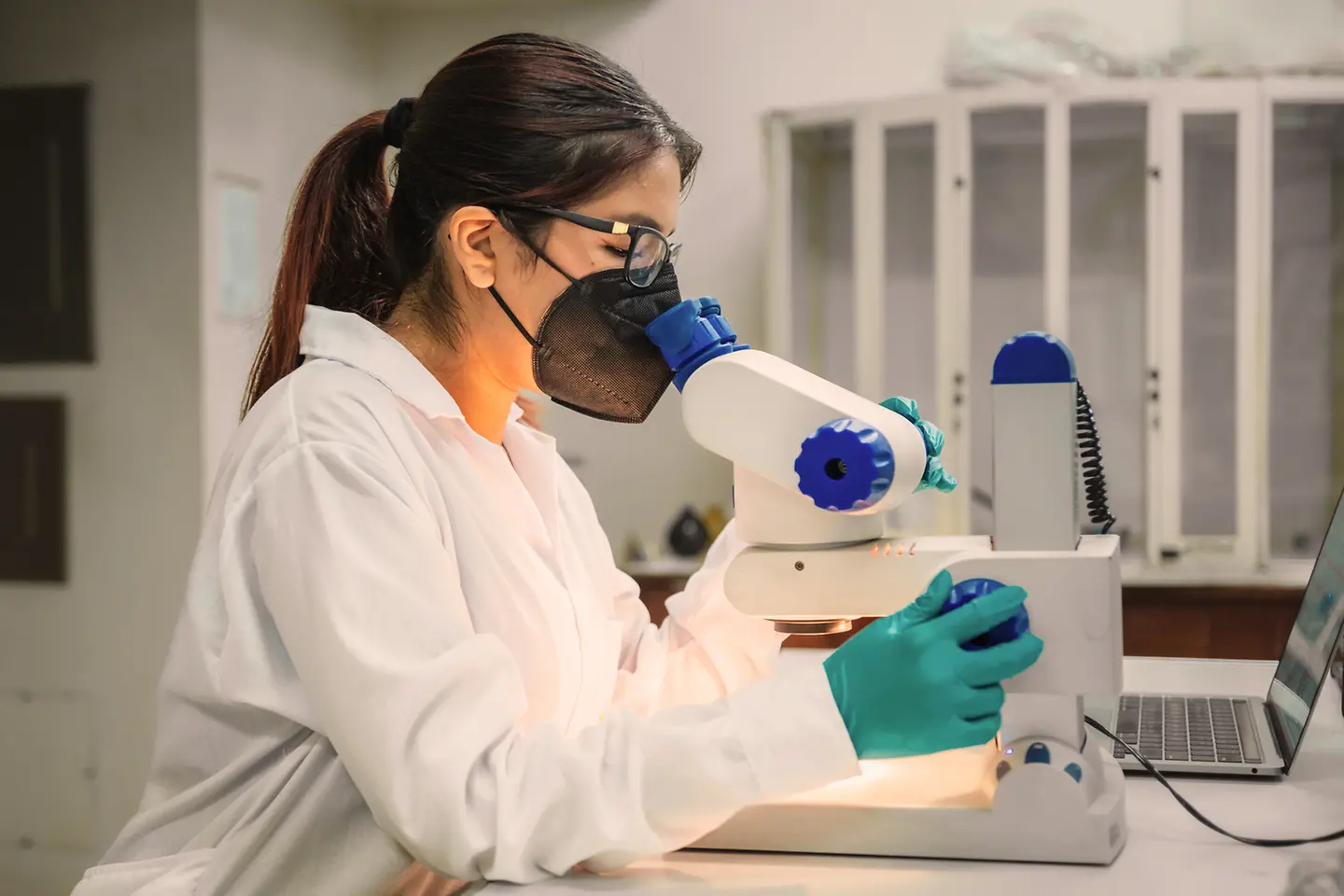 Forscherin im Labor schaut durch ein Mikroskop