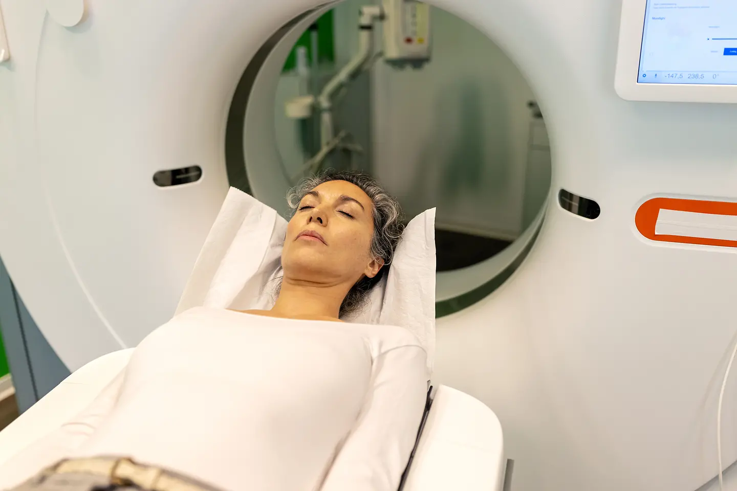 Eine Frau auf einer Therapieliege erhält eine Computertomografie (CT) am Kopf.