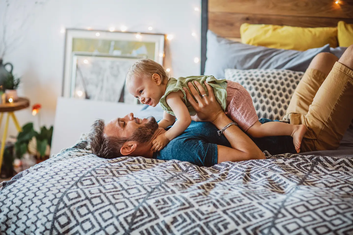 Ein Vater spielt mit einem kleinen Kind auf dem Bett