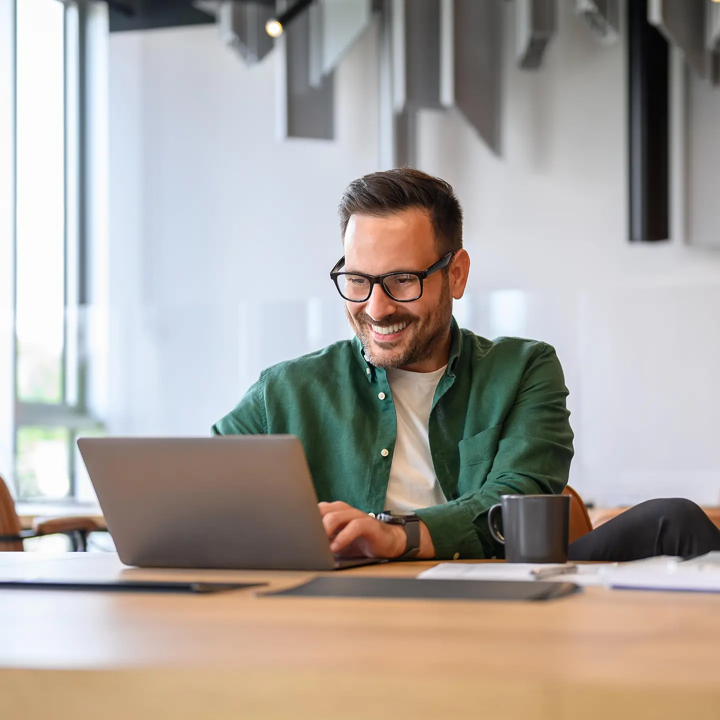 Ein junger IT-Mitarbeiter arbeitet an einem Laptop in einem modernen Büro