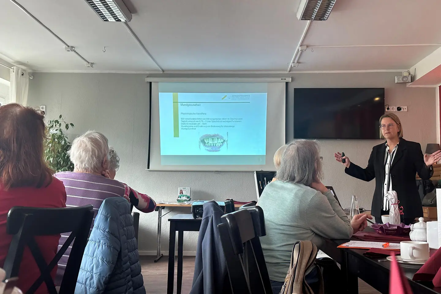 Eine Frau hält einen Vortrag vor Senioren.