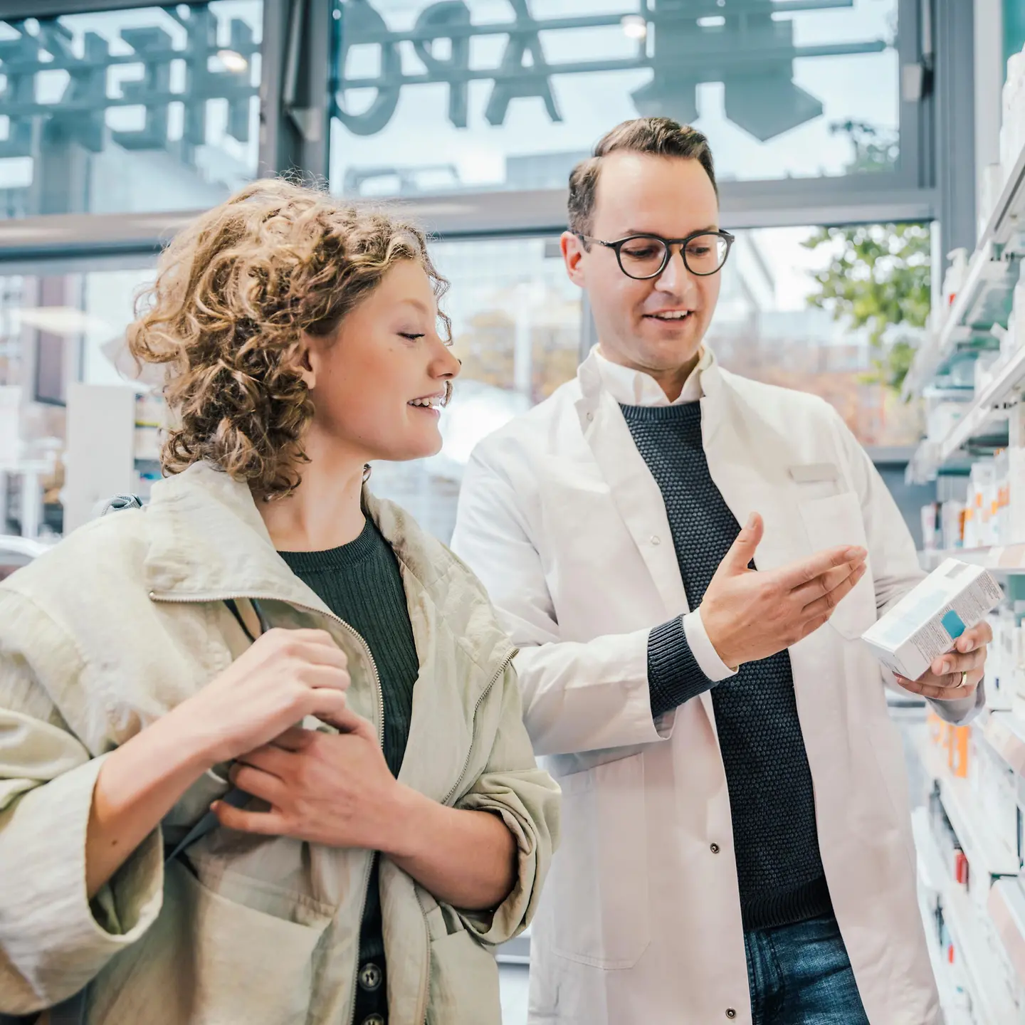 Ein Apotheker berät eine Versicherte zu einem Arzneimittel