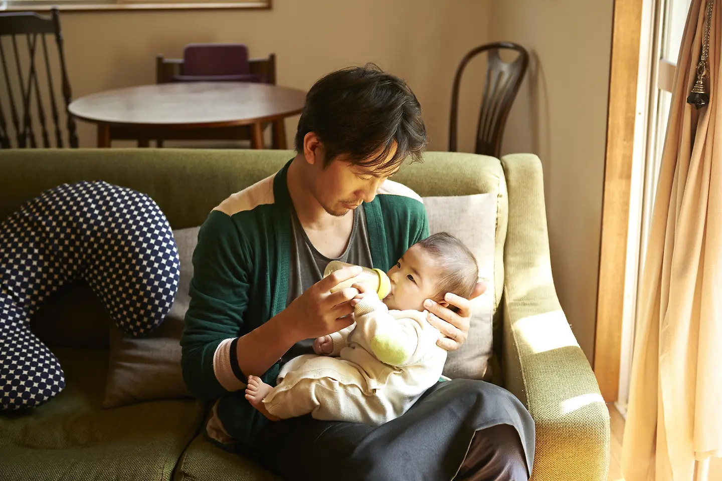 Junger Mann gibt einem neugeborenen Baby ein Milchfläschchen