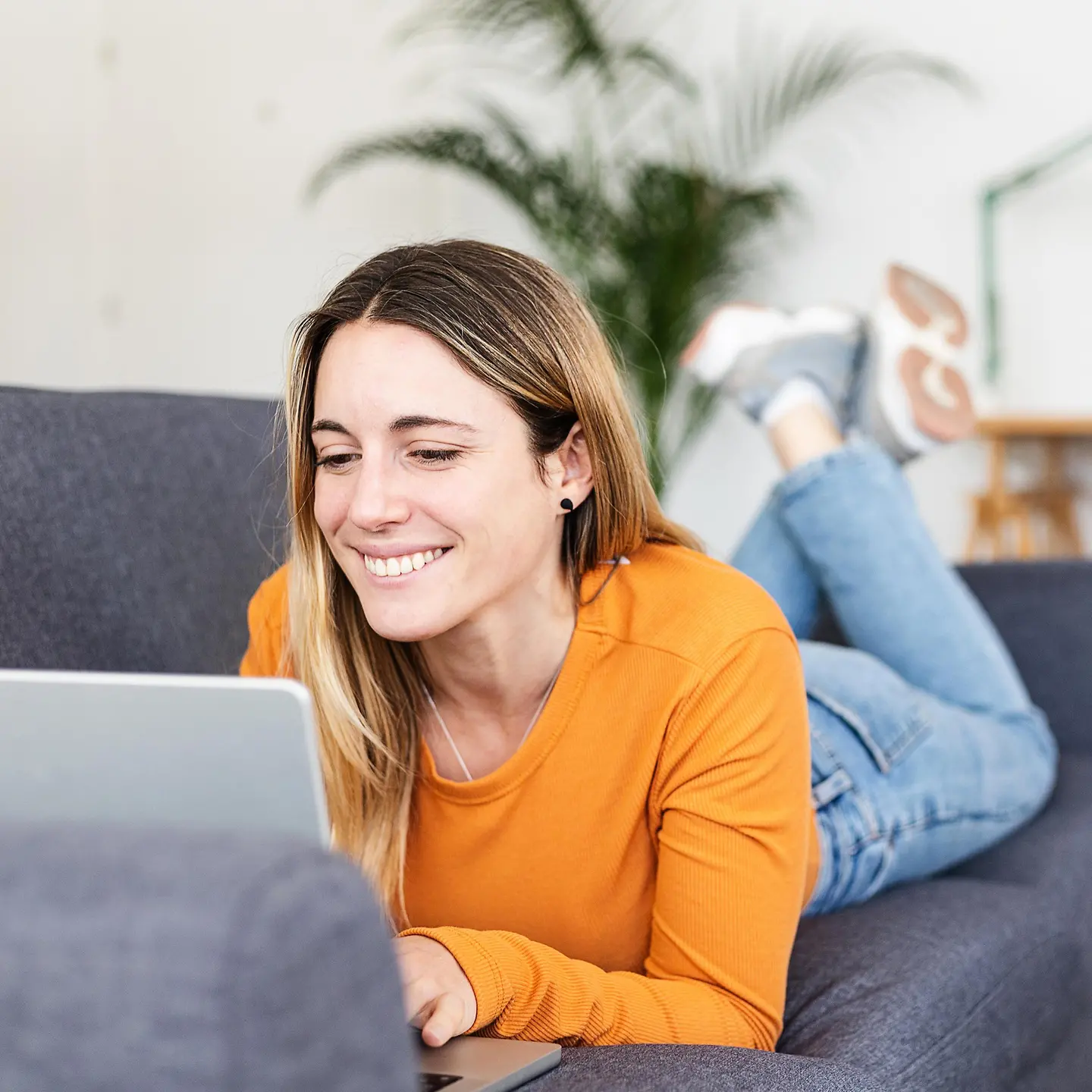 Eine glückliche Frau mit Laptop auf dem Sofa