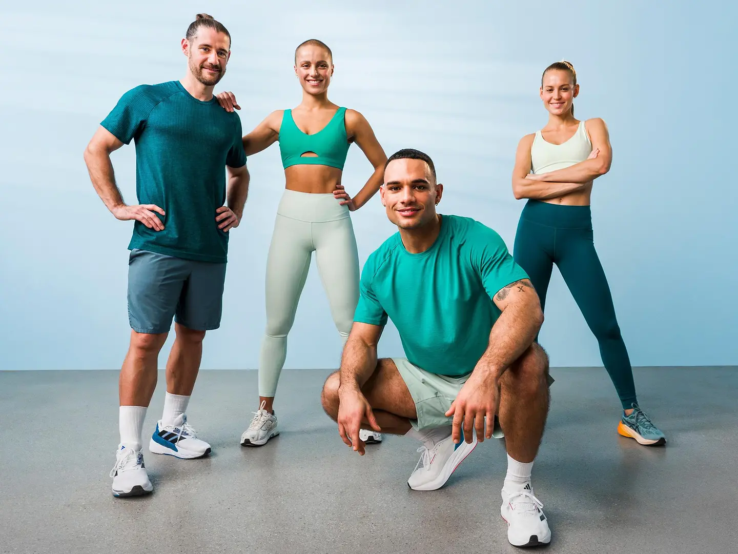 Eine Gruppe von vier Menschen in Sportklamotten steht in einem Raum