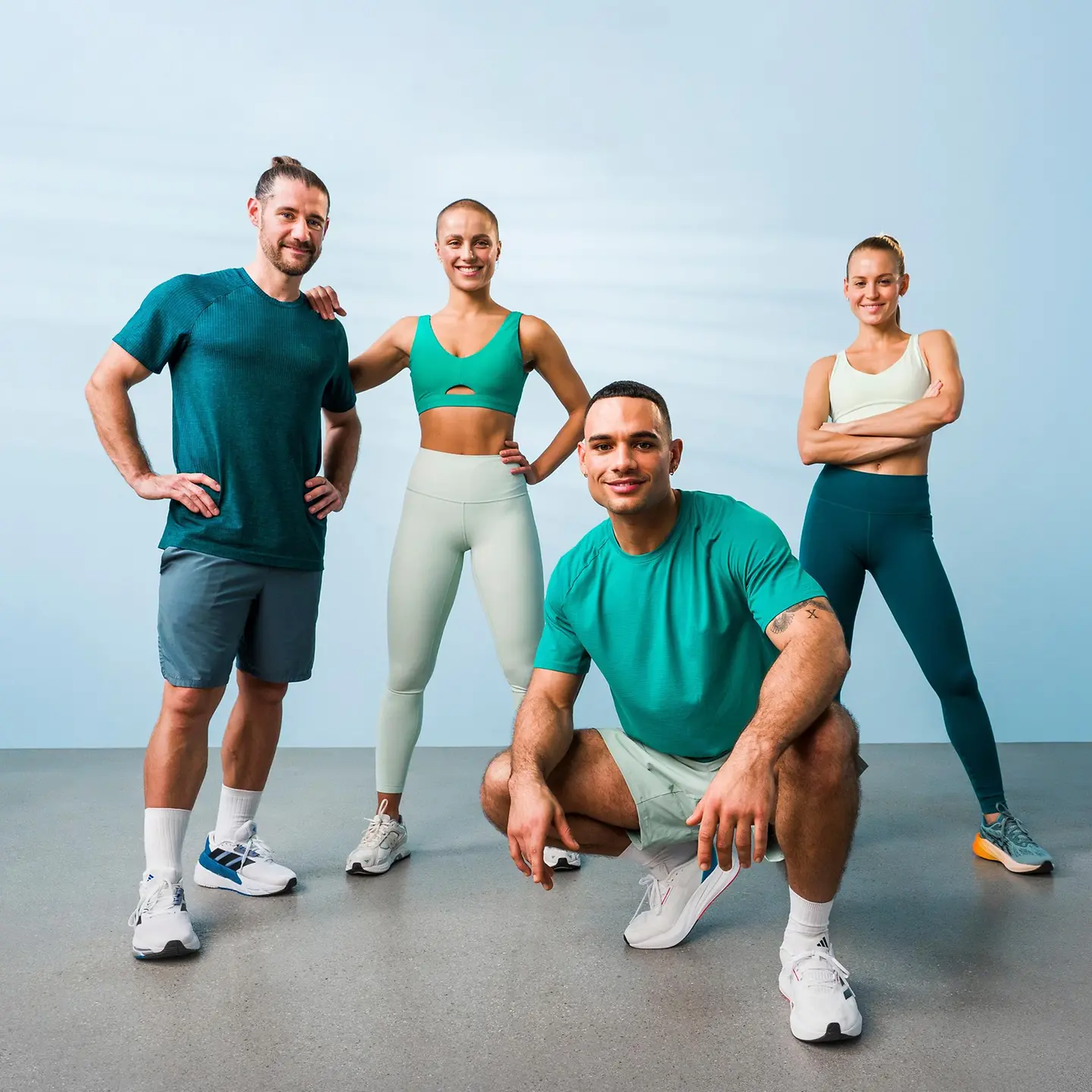 Eine Gruppe von vier Menschen in Sportklamotten steht in einem Raum