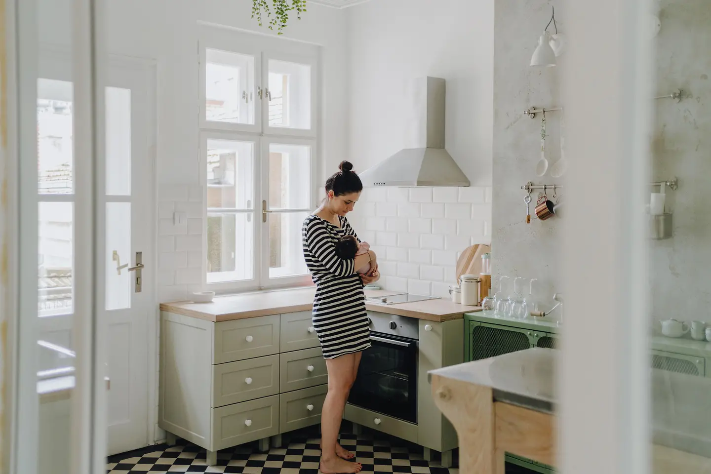 Eine Frau steht in einer Küche und hält ein neugeborenes Baby