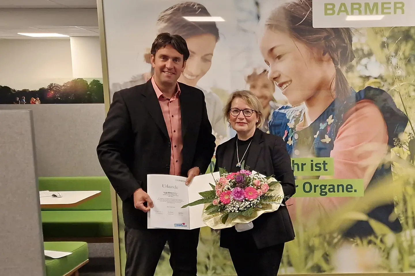 Dominik Werle überreicht Anja Watermann eine Urkunde und einen Blumenstrauß.