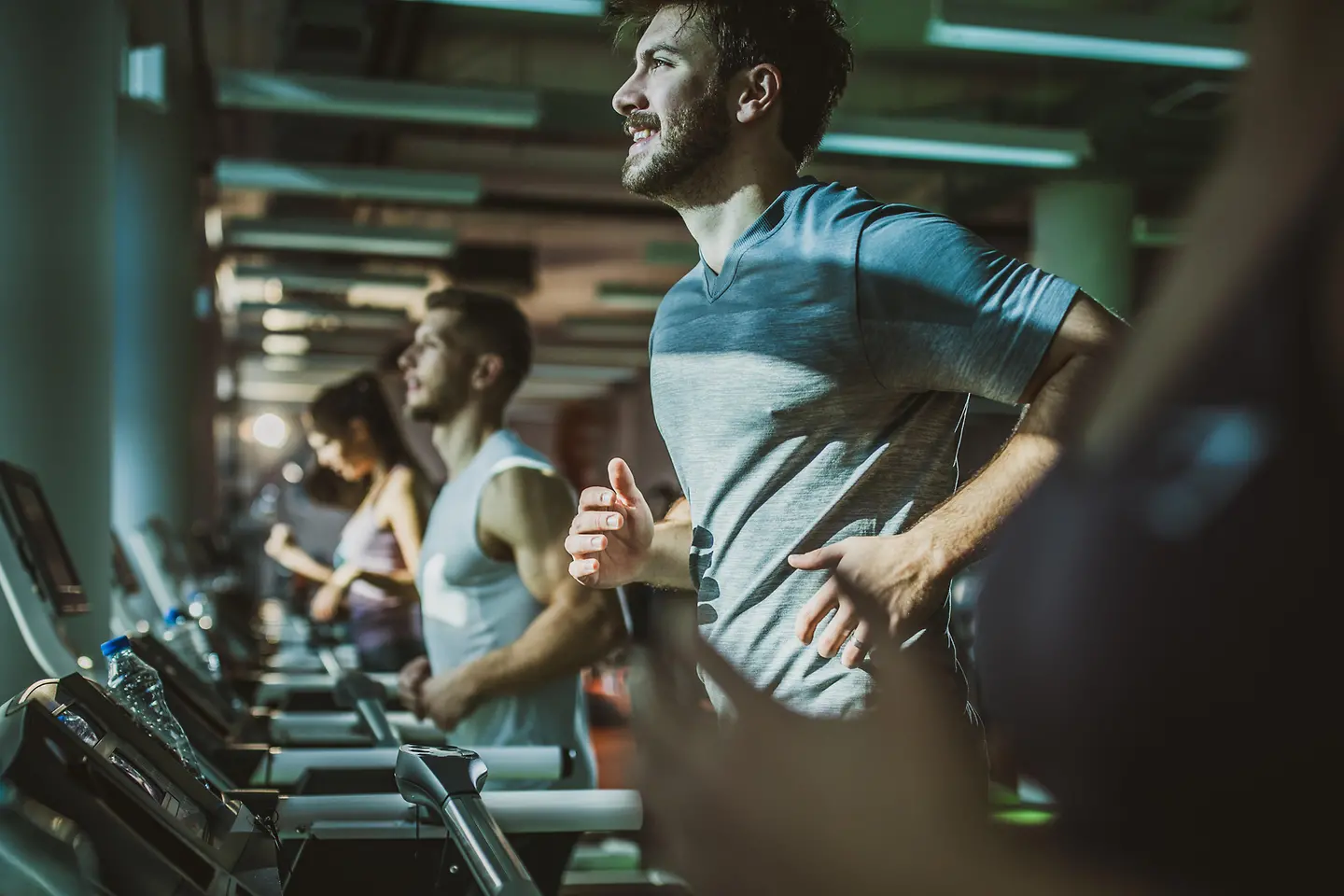Junge Männer laufen im Fitnessstudio auf dem Laufbahn