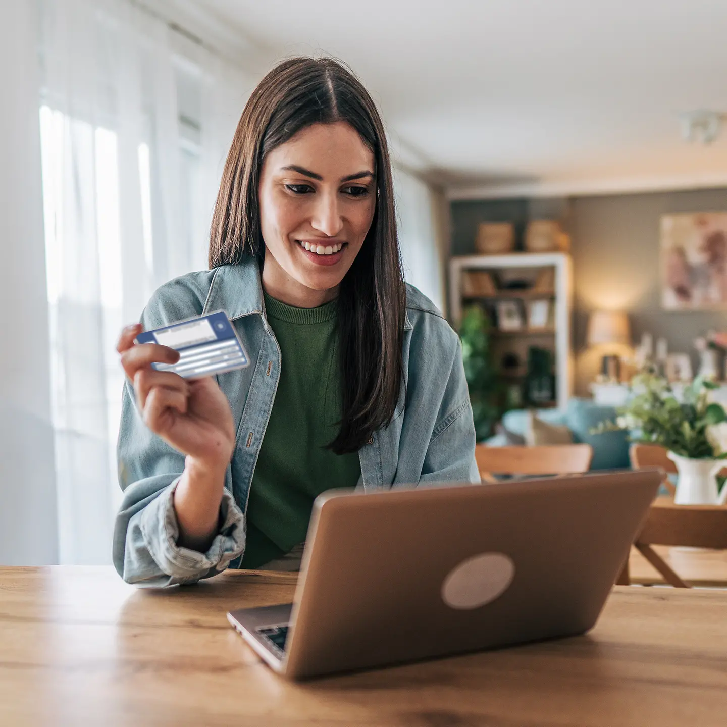 Junge Frau mit Chipkarte zuhause am Tisch mit Laptop