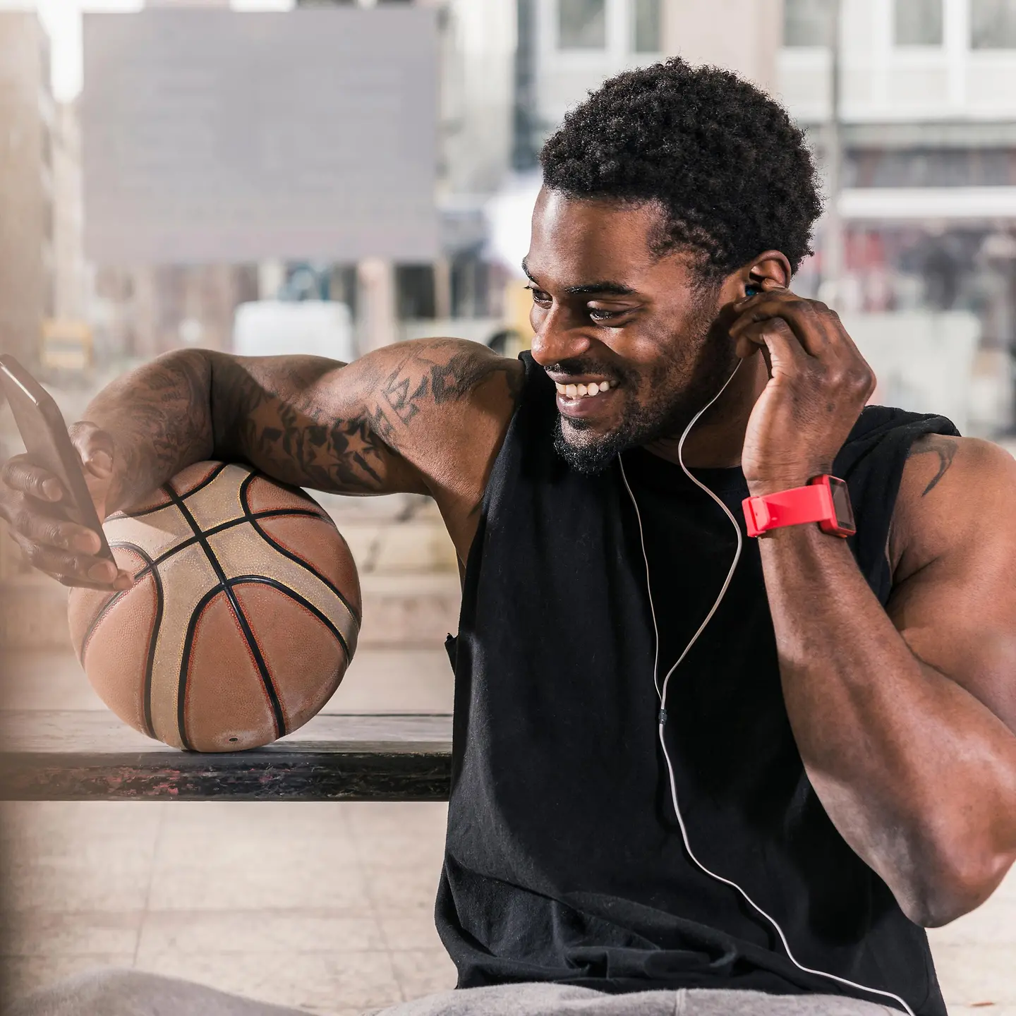 Ein junger Basketballspieler mit Smartphone und Smartwatch