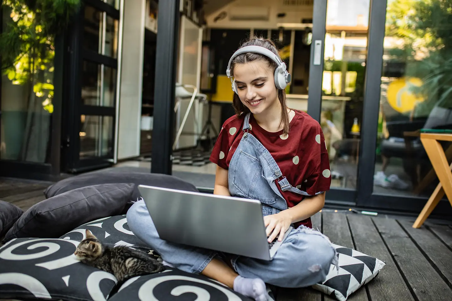 Eine junge Frau mit Kopfhörer arbeitet zuhause an ihrem Laptop