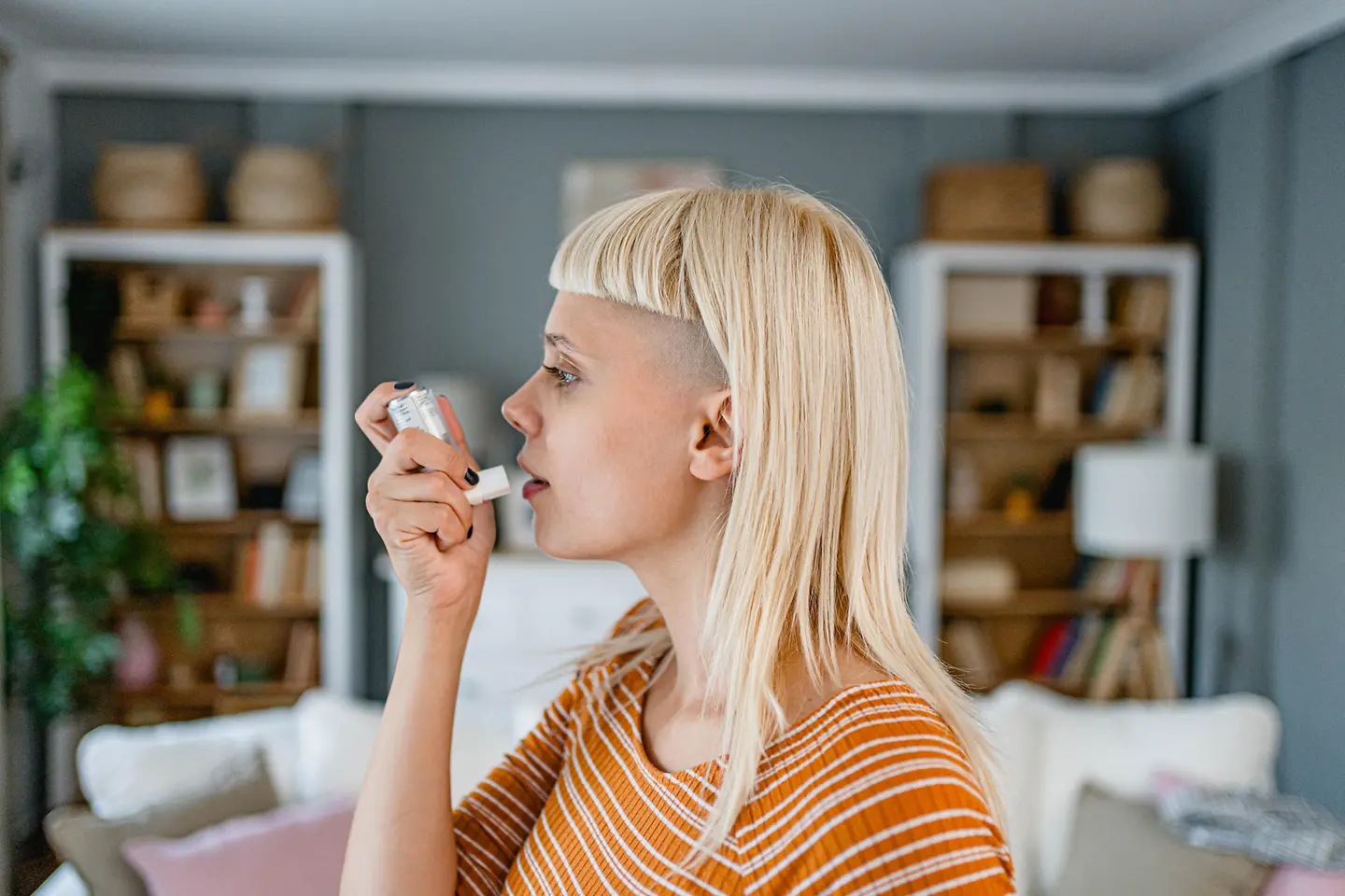 Junge Frau benutzt einen Asthma-Inhalator