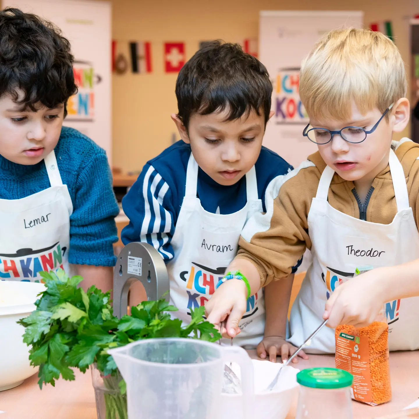 Drei Jungen schmecken in der Kita gemeinsam ein Essen ab