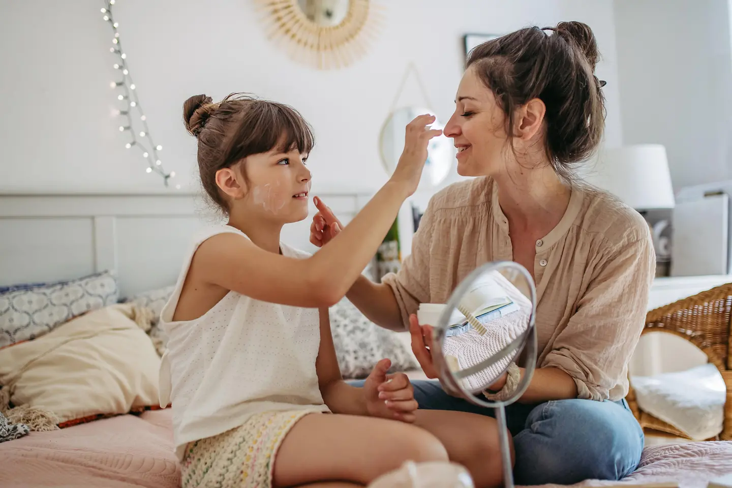 Mutter und Tochter cremen sich gegenseitig das Gesicht ein