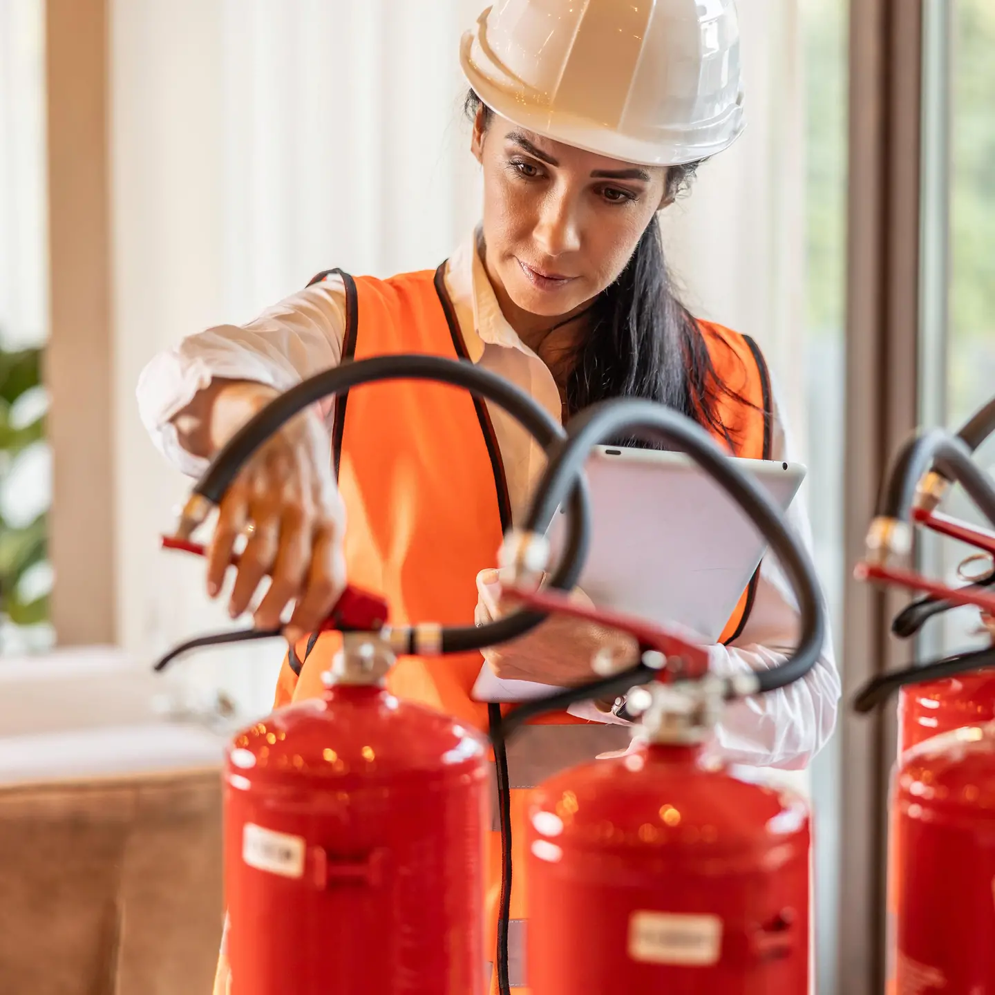 Eine Sicherheitsinspektorin prüft die Feuerlöscher im Hotelrestaurant.