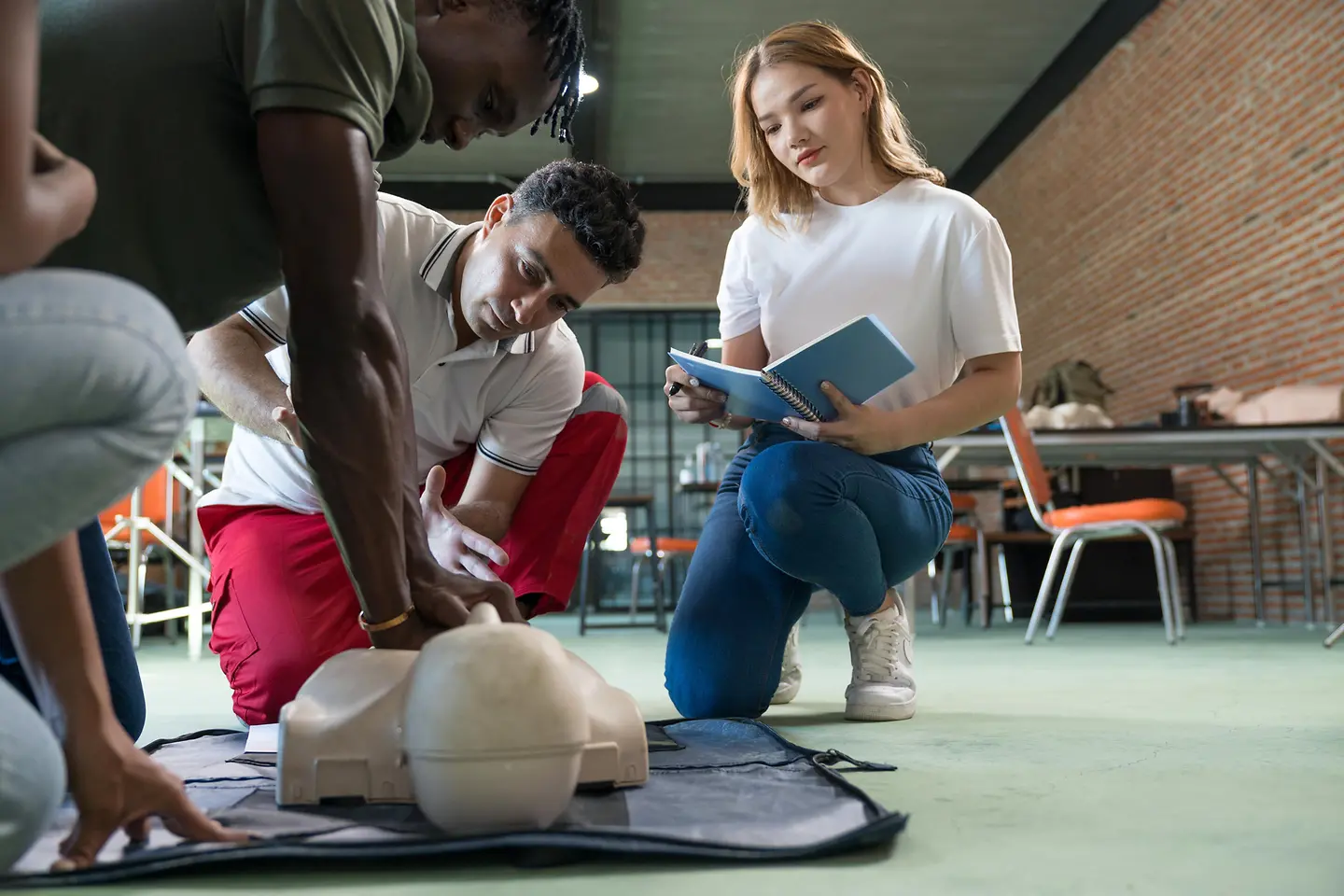 Vier Personen üben die praktische Erste-Hilfe am Modell.