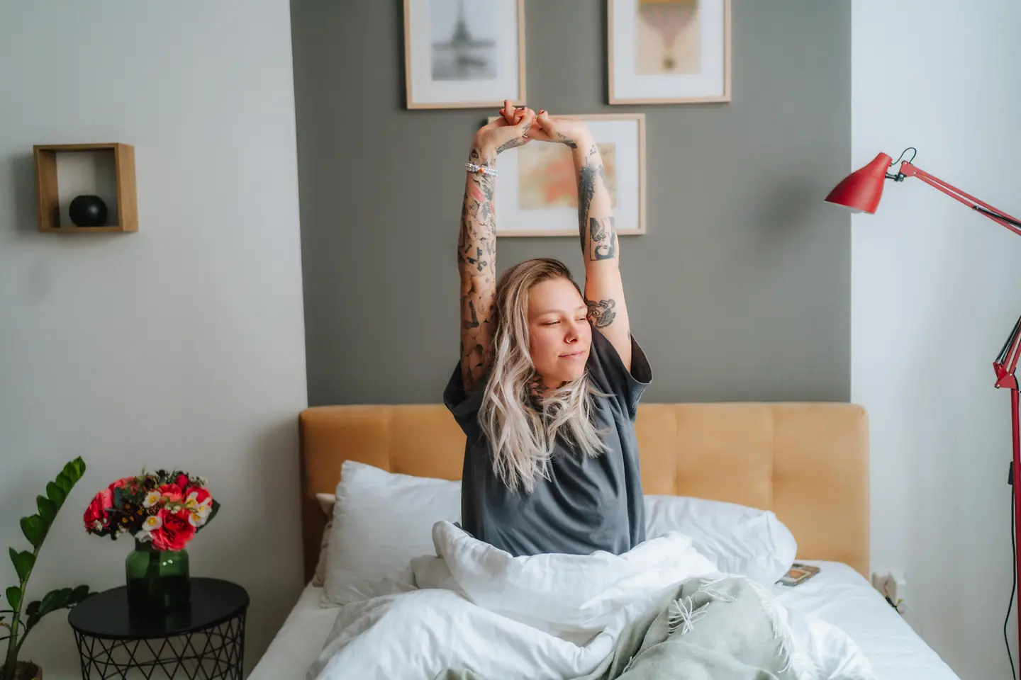 Eine junge Frau streckt sich morgens in ihrem Bett