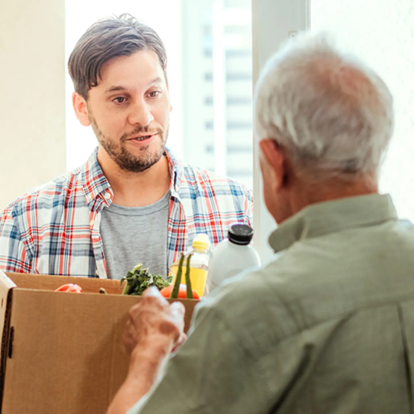 Junger_Mann_bringt_altem_Mann_Einkäufe