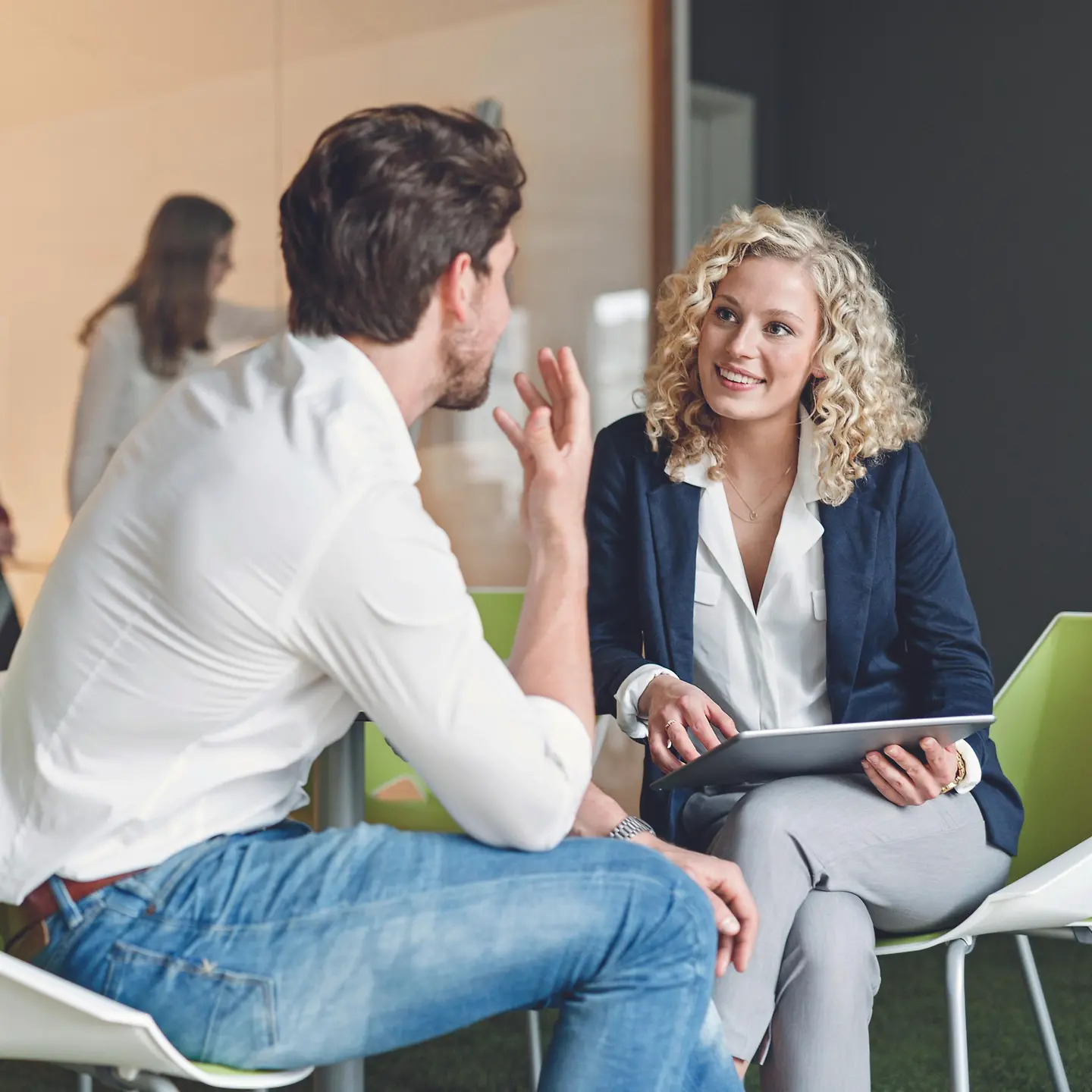 Zwei Kollegen sitzen sich im Büro gegenüber und unterhalten sich.