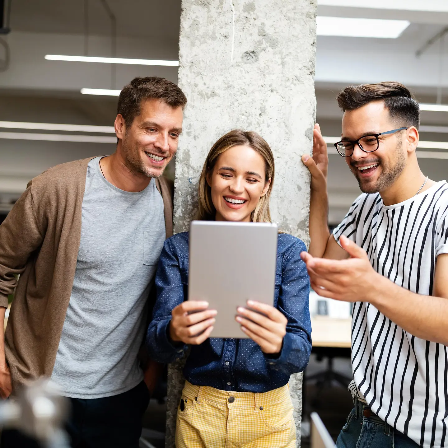 Zufriedene Mitarbeitende in einem modernen Büro mit Tablet