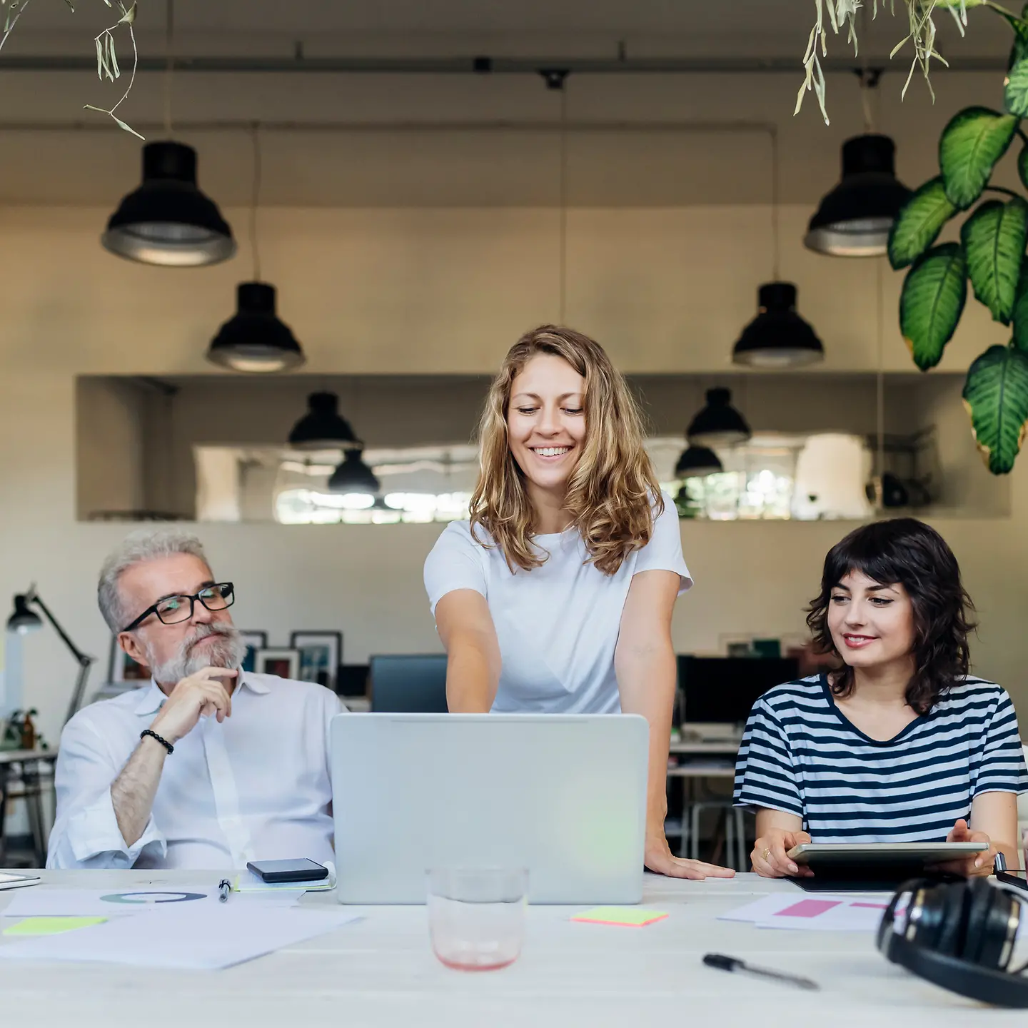Eine Geschäftsfrau präsentiert am Laptop vor einem Team
