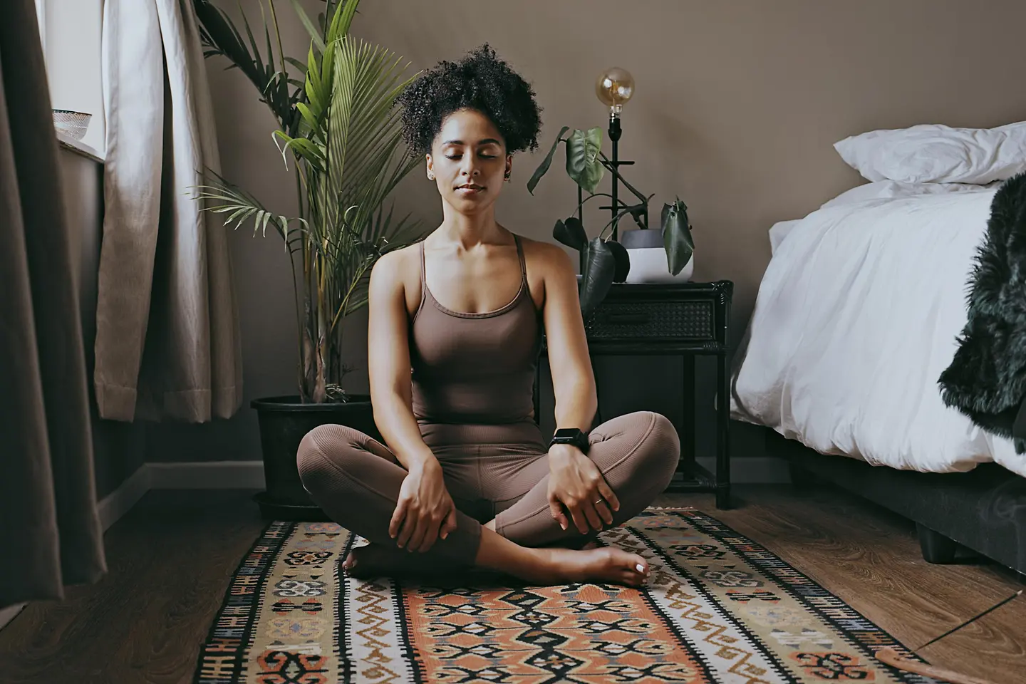 Eine Frau sitzt im Schneidersitz und meditiert mit geschlossenen Augen