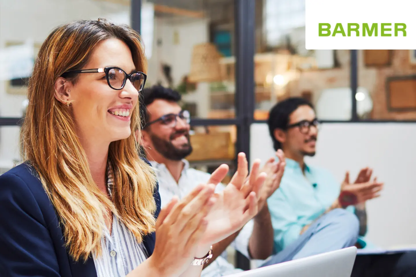 Eine Frau und zwei Männer applaudieren