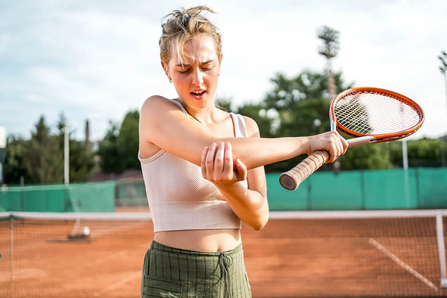 Eine Tennisspielerin fasst sich mit schmerzverzerrtem Gesicht an den Ellenbogen