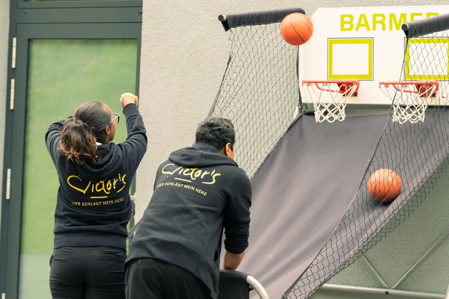 Ein Mann und eine Frau werfen Basketbälle in Basketballkörbe.