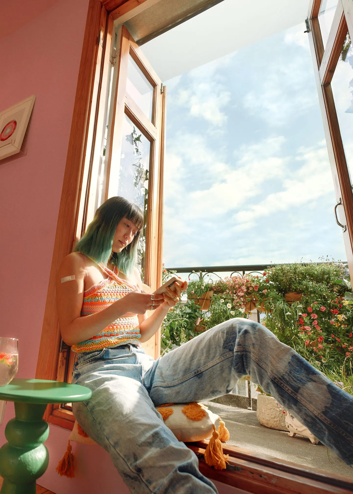 A woman is sitting by the window holding a smartphone on which she is using the Barmer app.