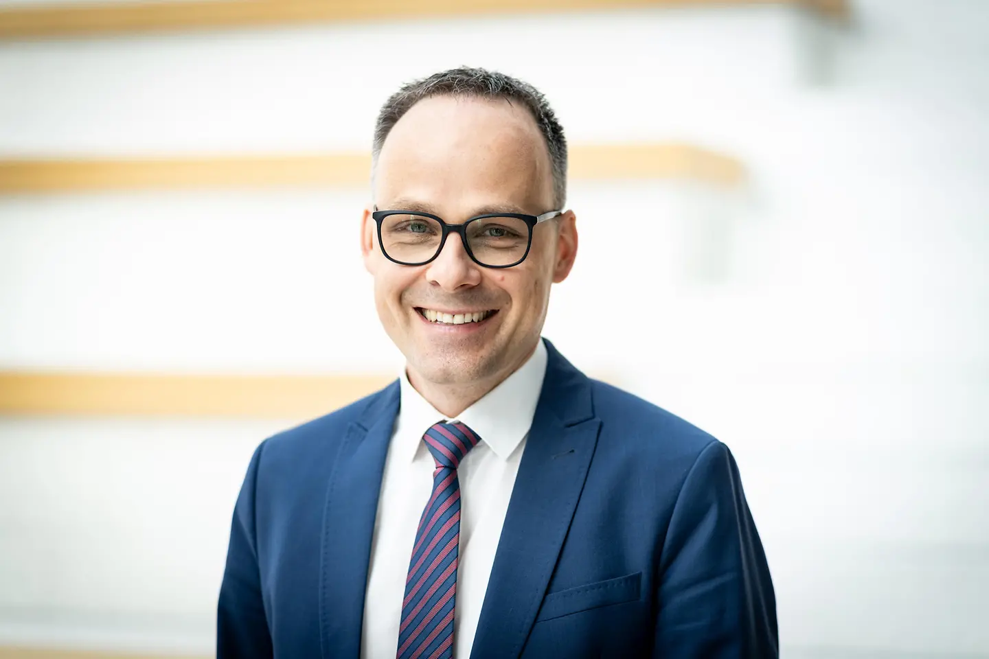 Denis Alt steht vor einer Wand.