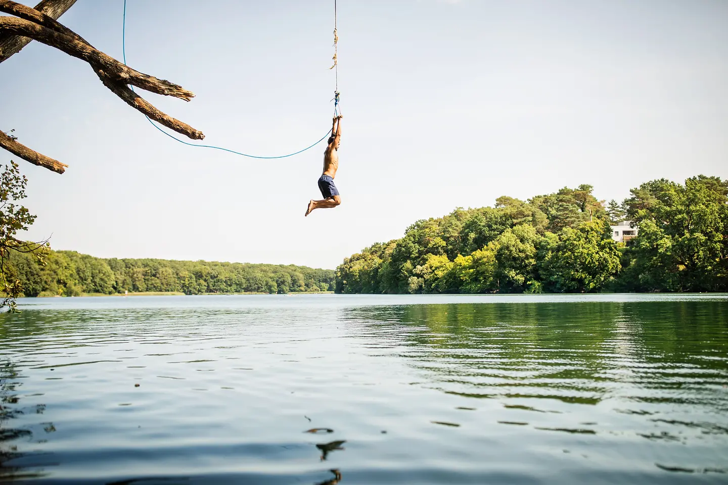 Mann schwingt an einem Seil und springt in einen See