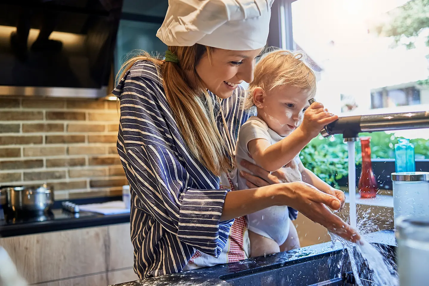 Kind und Mutter waschen Hände am Wasserhahn in der Küche