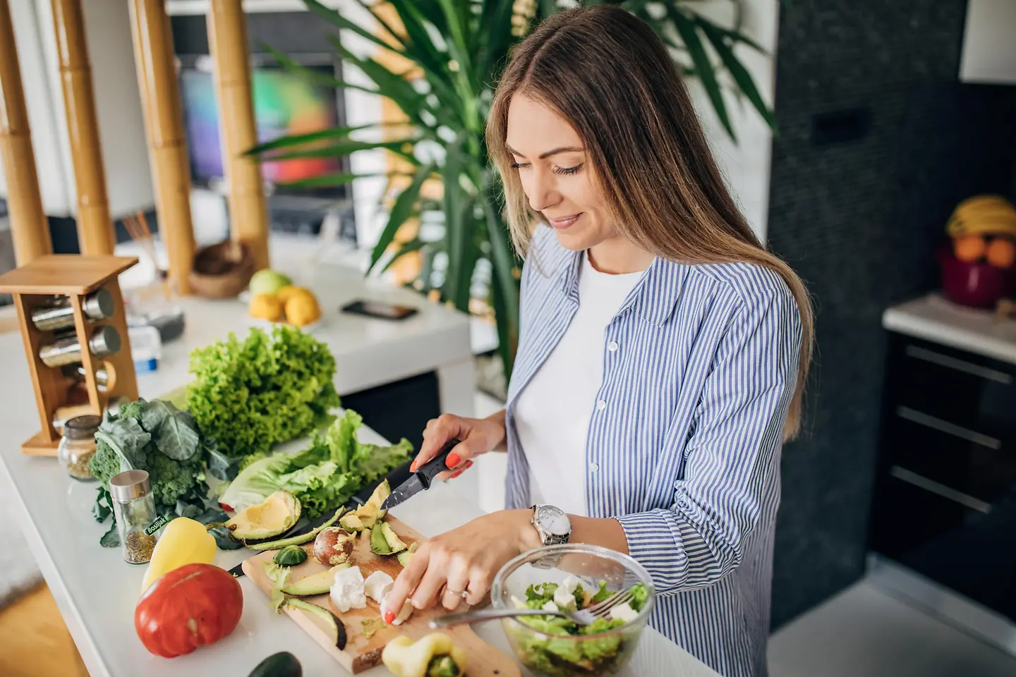 Eine Frau bereitet sich in der Küche einen gesunden Salat zu