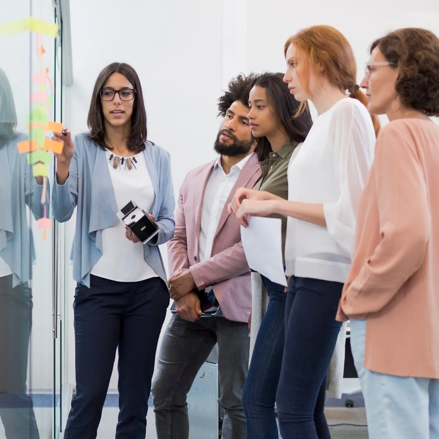 Eine Gruppe von Mitarbeitenden brainstormed vor einer Glaswand